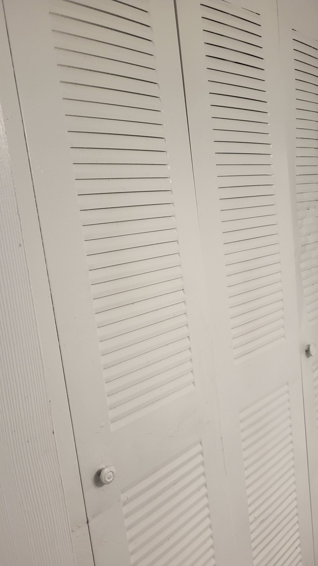 A white closet with a sliding door.