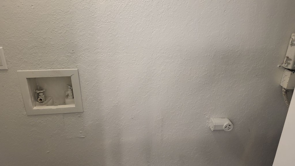 A white wall with a socket and a switch.