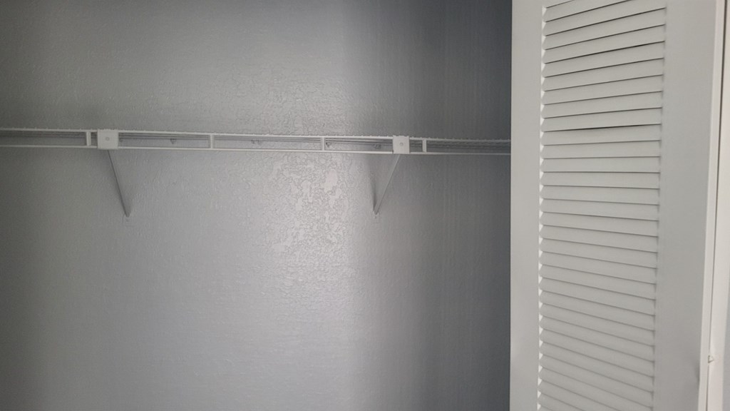 A wall with a shelf and a door with blinds.