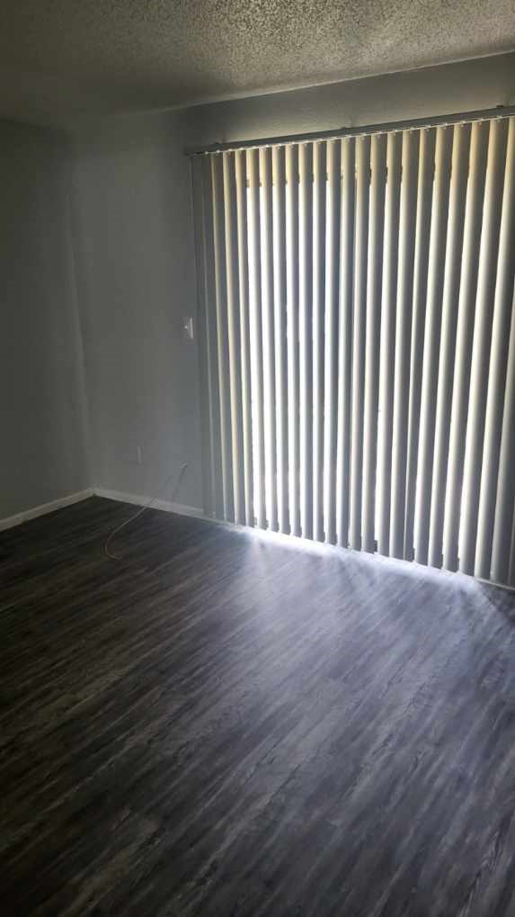 A room with a window covered by vertical blinds.