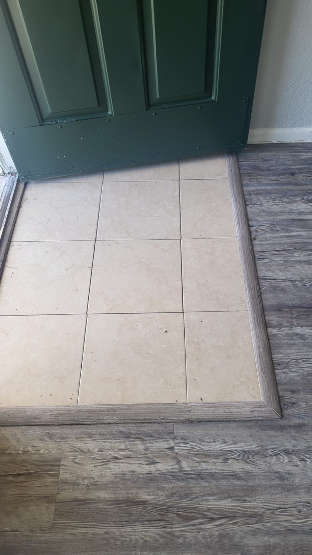 A white tile floor with a green door.