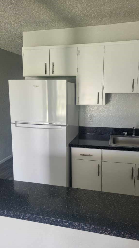 A white refrigerator and cabinets in a kitchen.