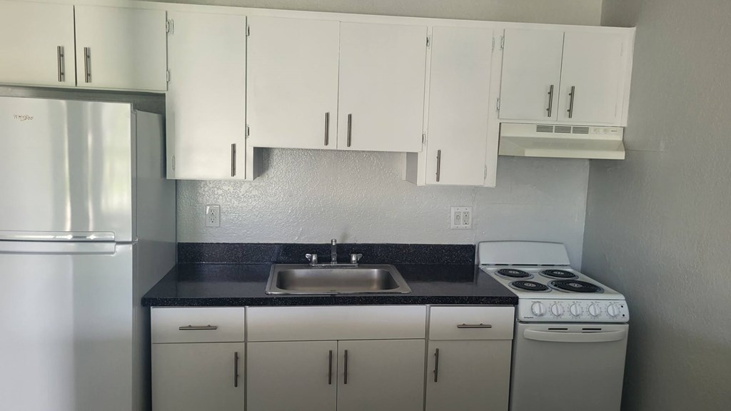A kitchen with white cabinets and a stove top oven.