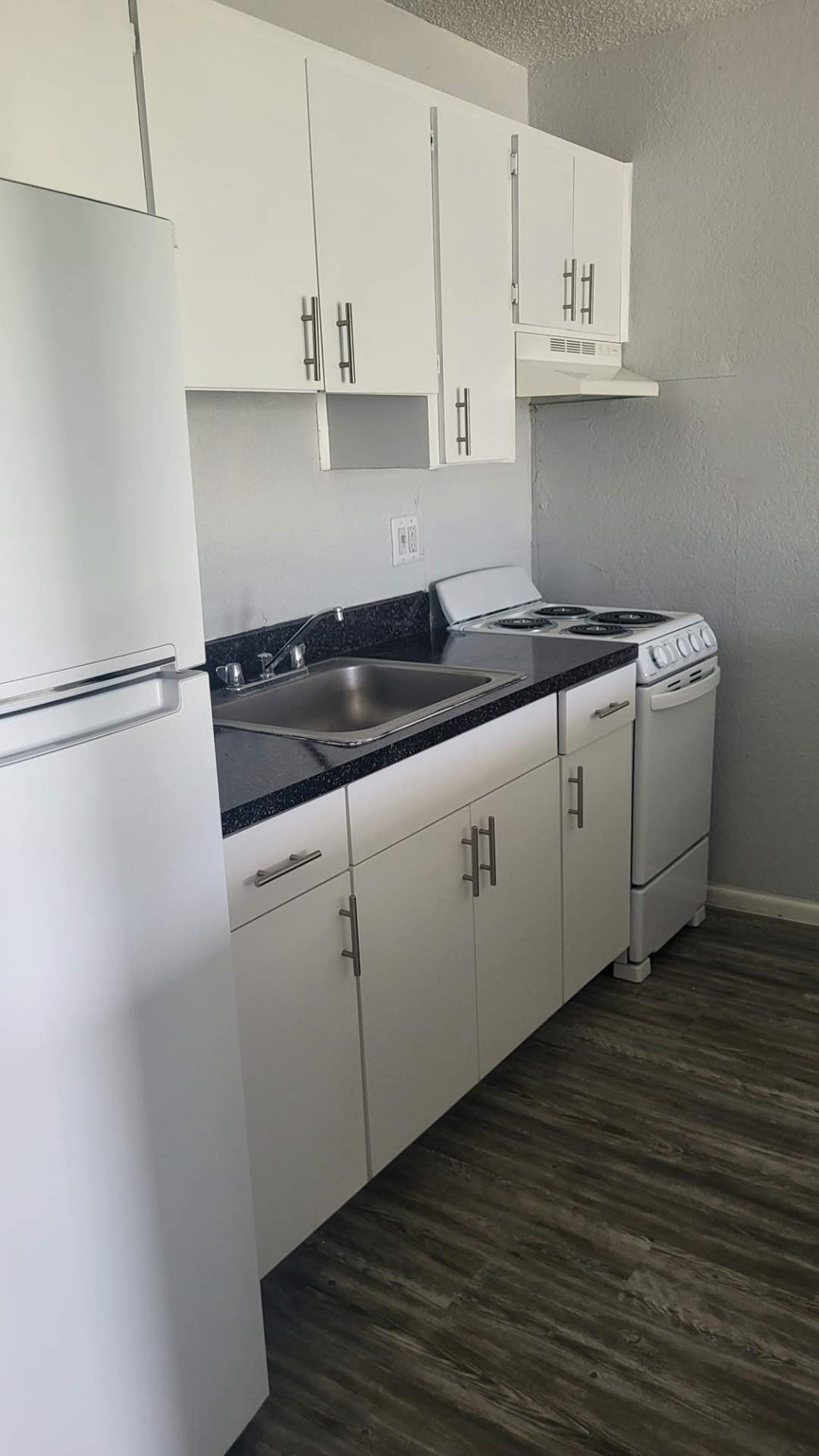 A kitchen with white cabinets and a black countertop.