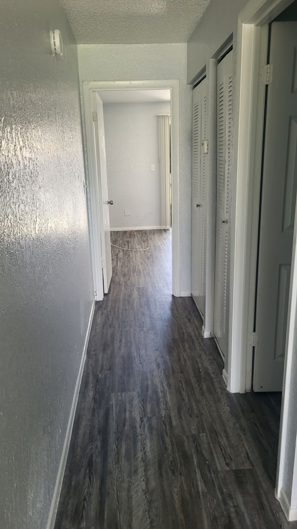 A long hallway with white doors and wood floors.