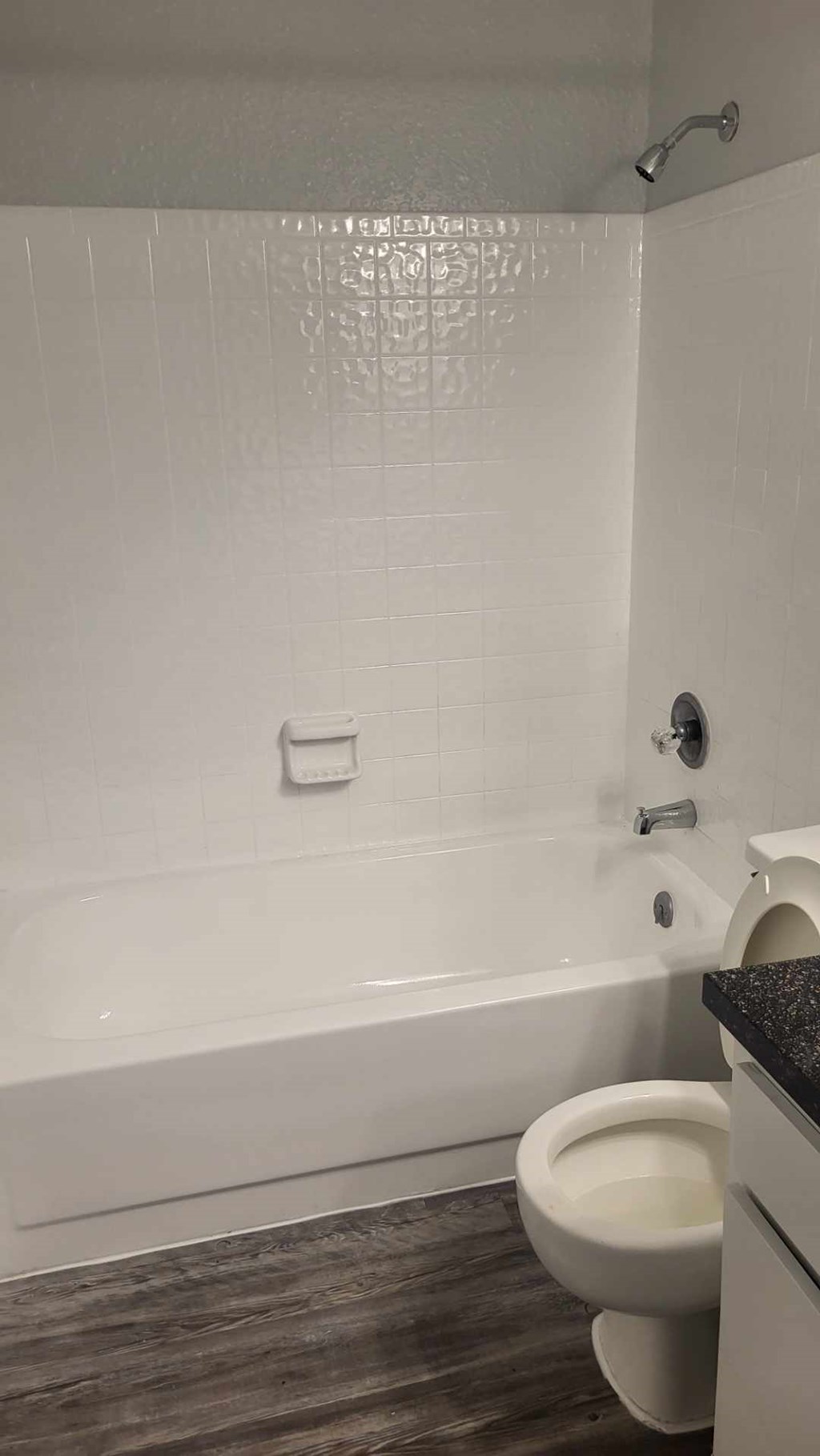 A white toilet in a bathroom with a white tiled wall.