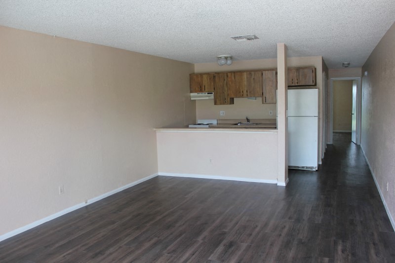 an empty living room and kitchen with a wood floor