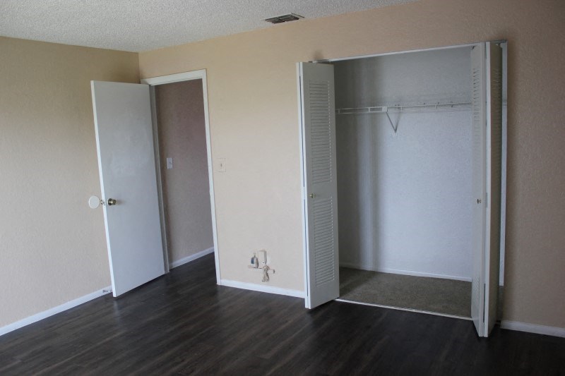 an empty bedroom with a closet and a hard wood floor