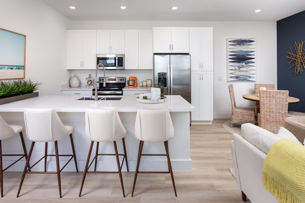 A modern kitchen with white cabinets and a large island with bar stools.