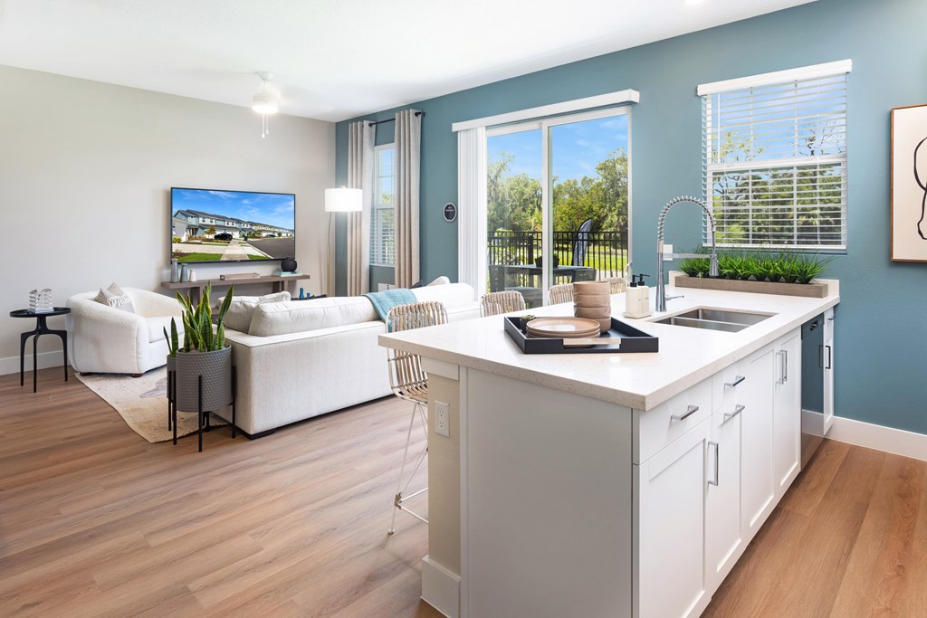 A modern kitchen and living room with a television and a view of the outdoors.