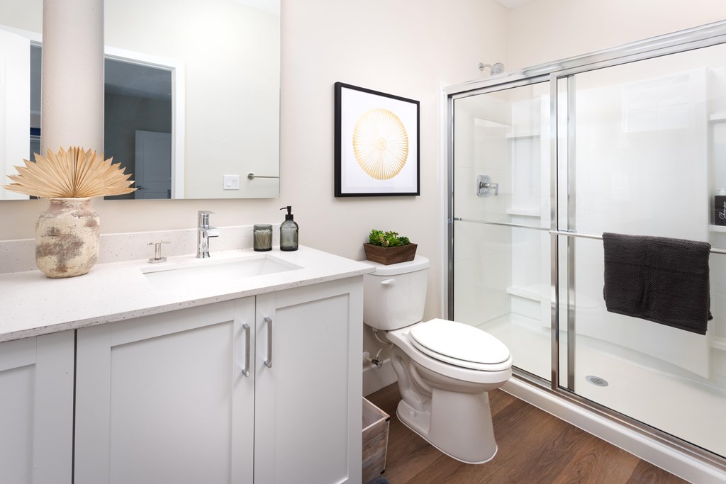 A white bathroom with a toilet, sink, and mirror.