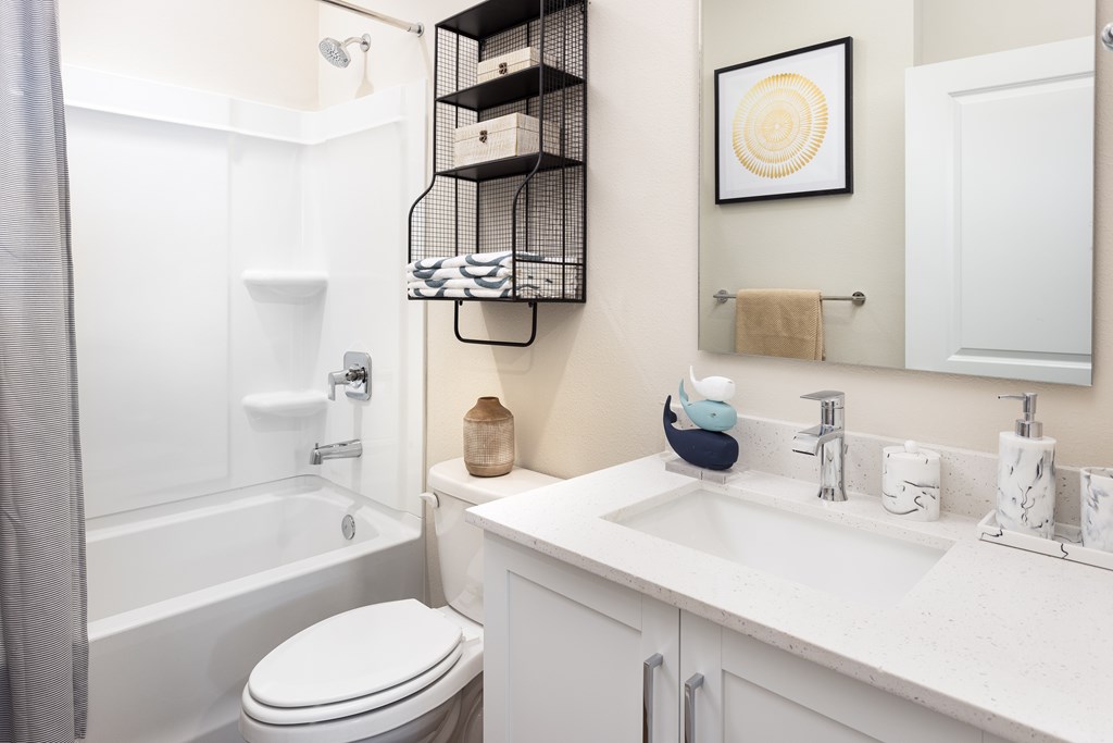 A white bathroom with a toilet, sink, and a shower.