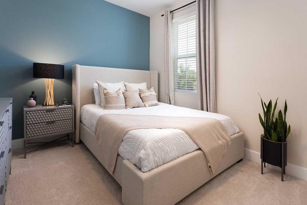A bedroom with a large bed and a potted plant.