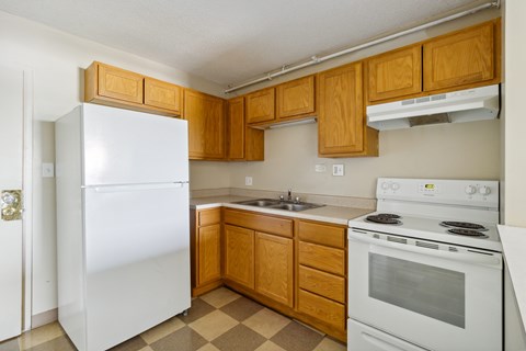 A kitchen with white appliances and wooden cabinets.