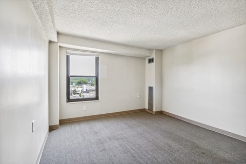 A room with a window and a carpeted floor.