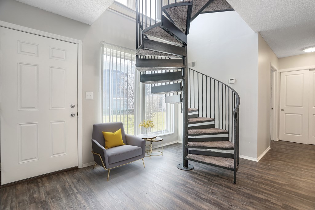 a living room with a spiral staircase and a chair