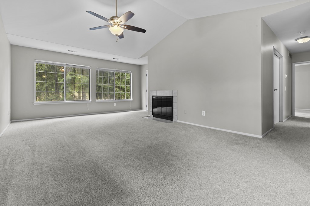 A spacious room with a ceiling fan and a fireplace.