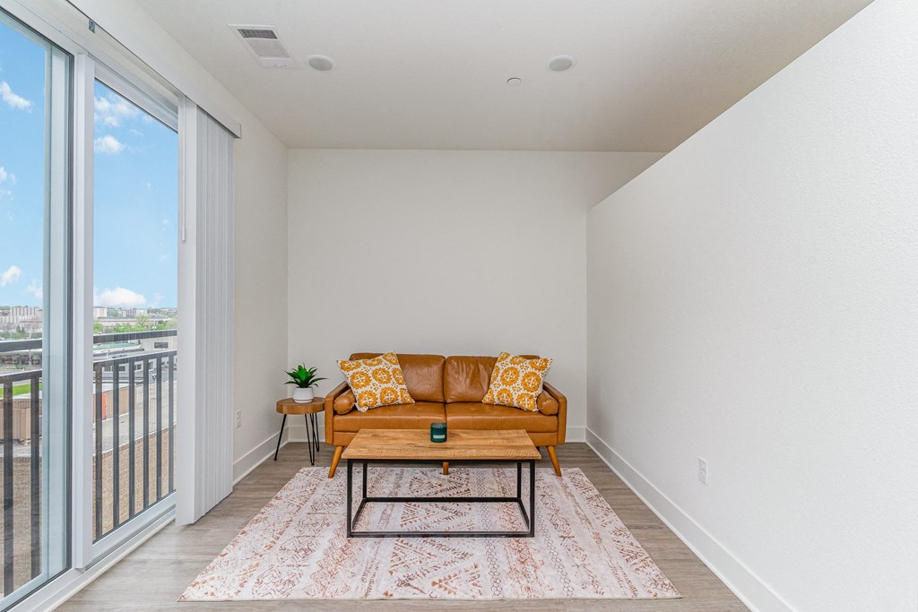 a living room with a couch and a coffee table and a balcony at City View Apartments, Lansing, Michigan