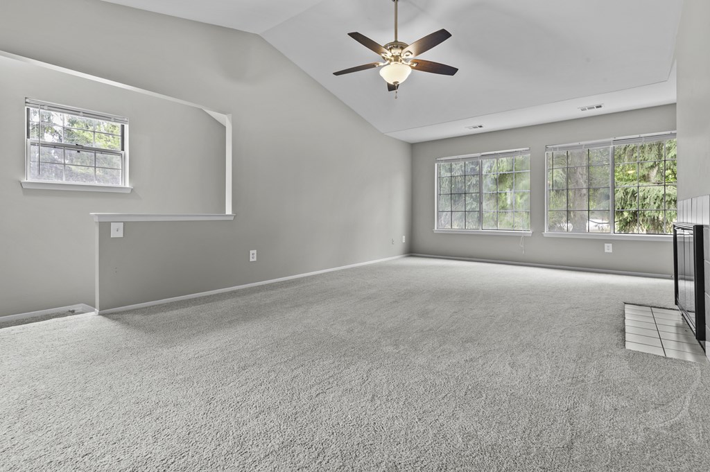 A spacious room with a ceiling fan and carpeted floor.