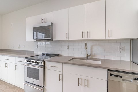 a kitchen with white cabinets and appliances and a sink