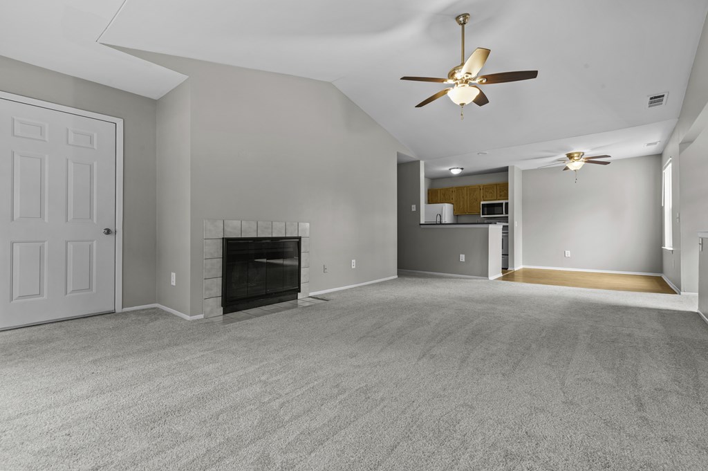 A spacious living room with a fireplace and a ceiling fan.
