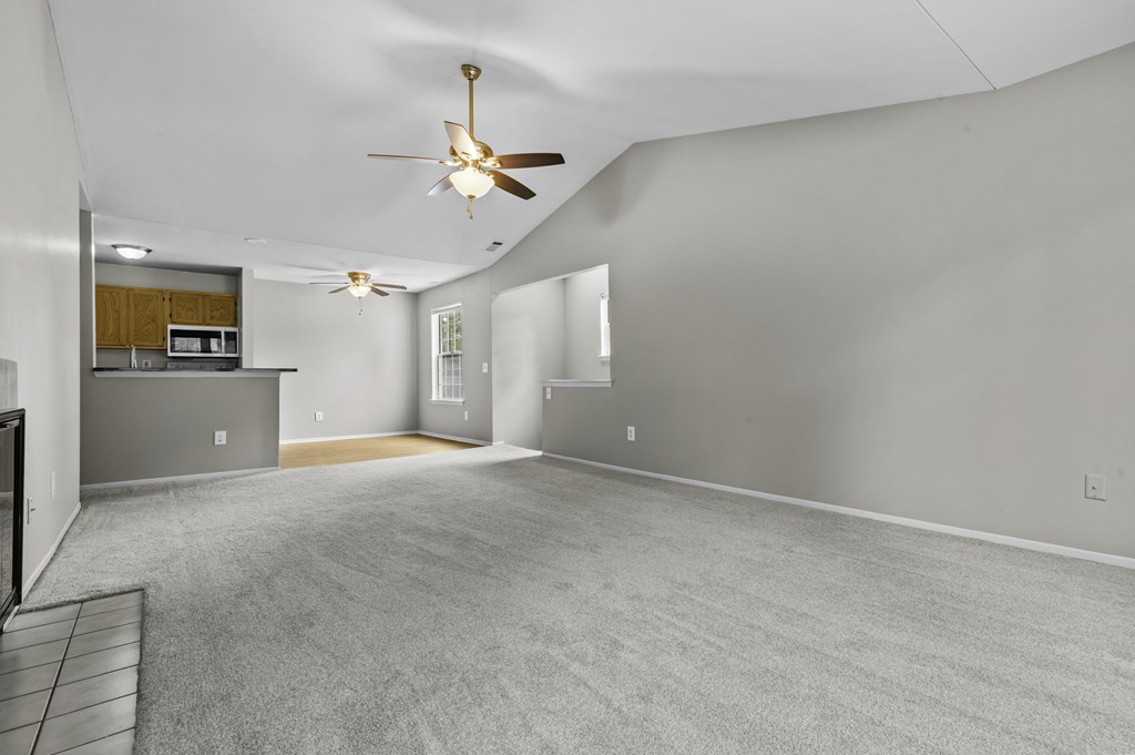 A spacious room with a ceiling fan and carpeted floor.