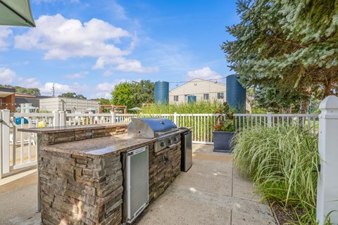 A patio with a stone counter and a white fence.