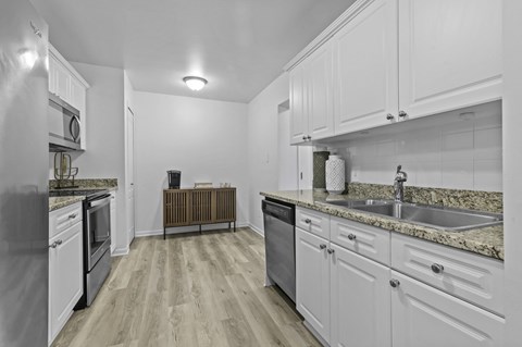 A kitchen with white cabinets and a granite countertop.