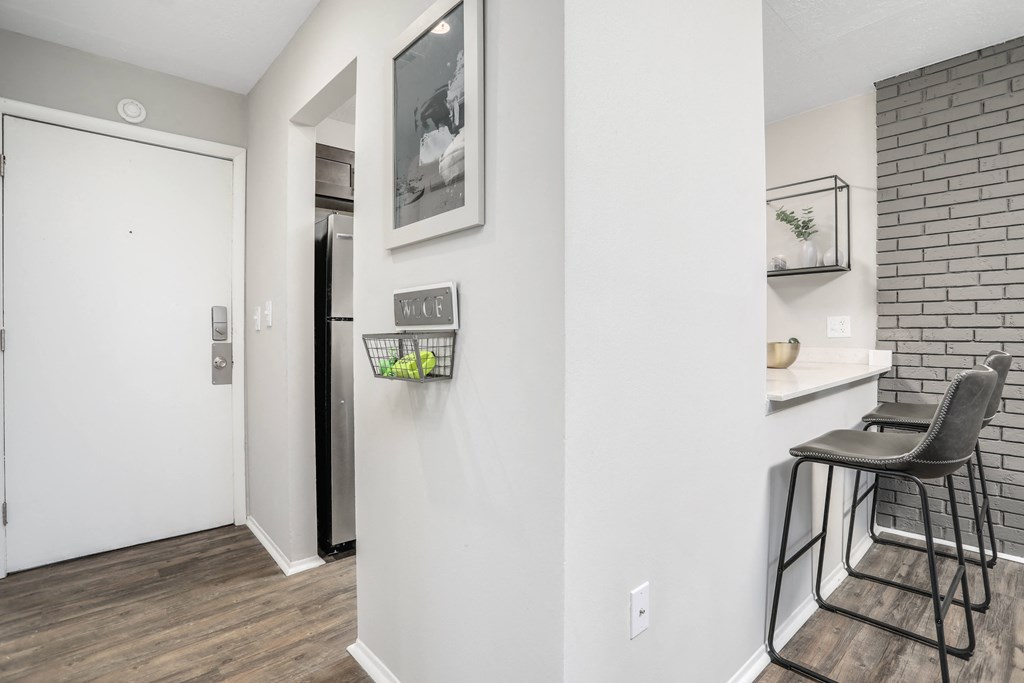 a living room with a white wall and a bar with a stool and a door