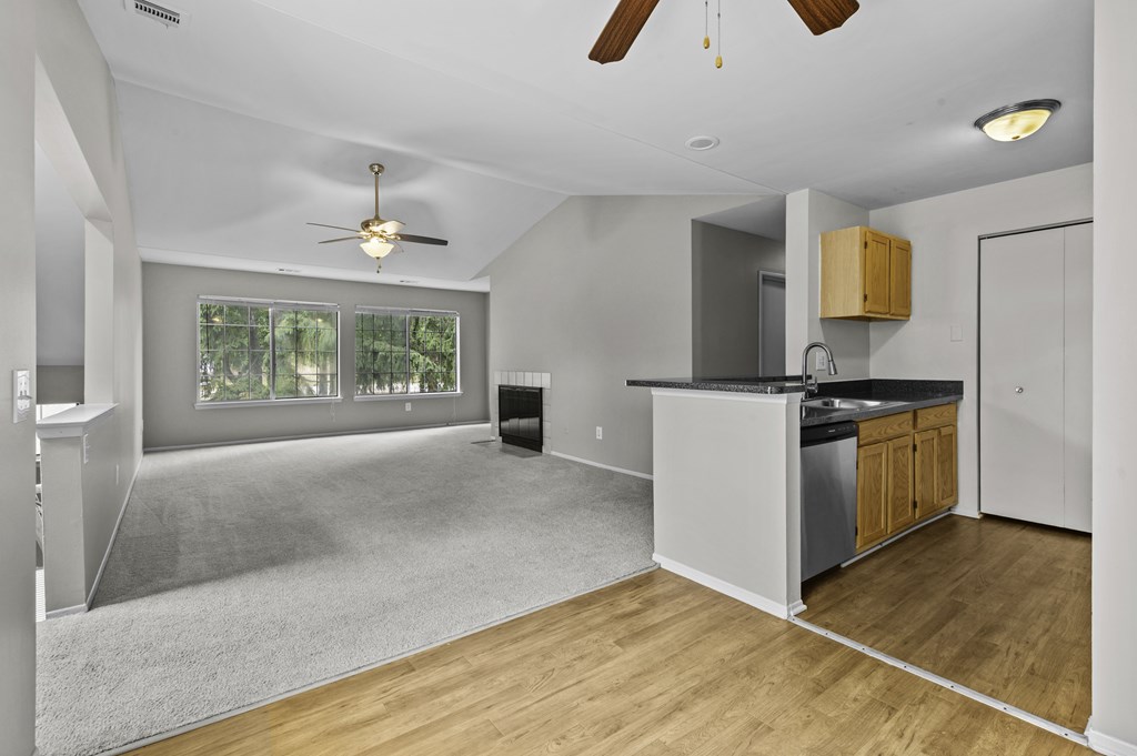 A spacious kitchen and living room with a ceiling fan and a large window.