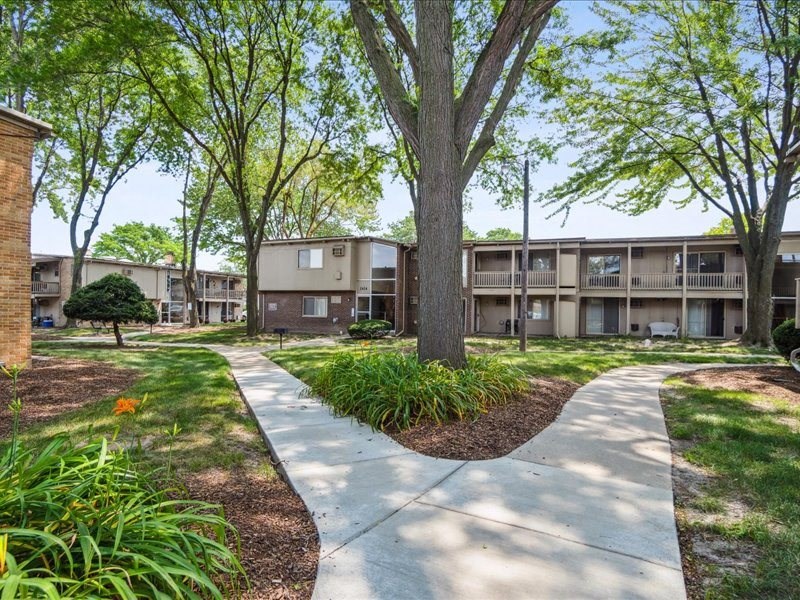 pathway leading to an apartment building with trees and grass