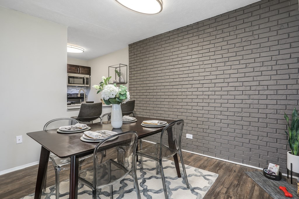 a dining room with a table and chairs and a brick wall