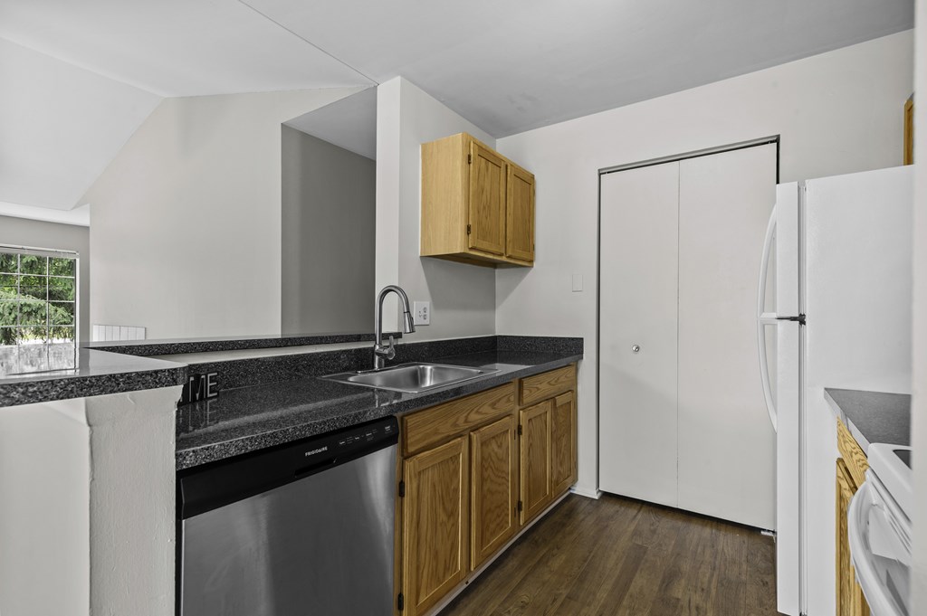 A kitchen with a black counter top and white appliances.