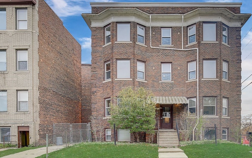an apartment building with a brick facade and a sidewalk