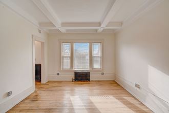 a living room with white walls and a window and a radiator