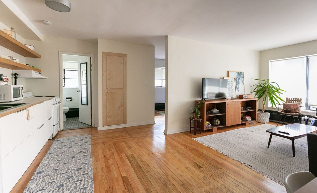 a kitchen and living room with wood floors and white cabinets