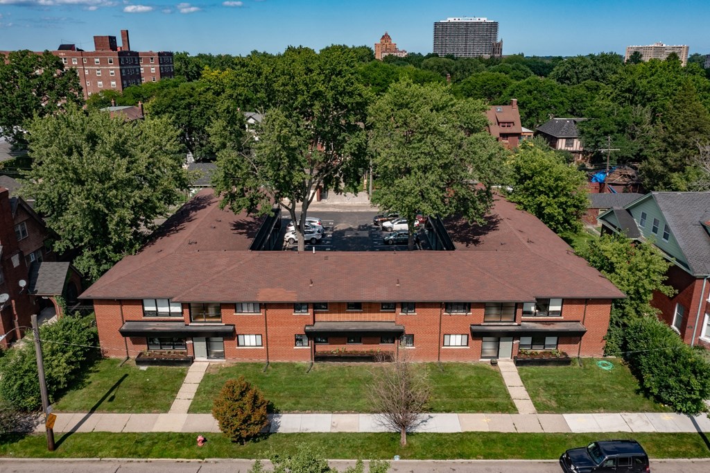 an aerial view of a brick building with trees and a city in the background