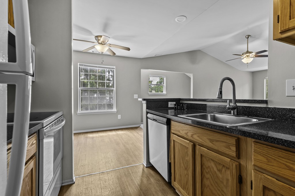 A modern kitchen with a black countertop and wooden cabinets.