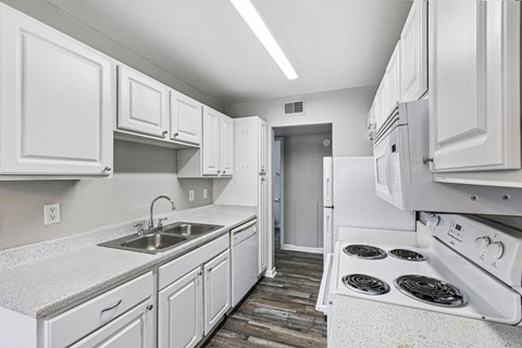 A kitchen with white cabinets and appliances.