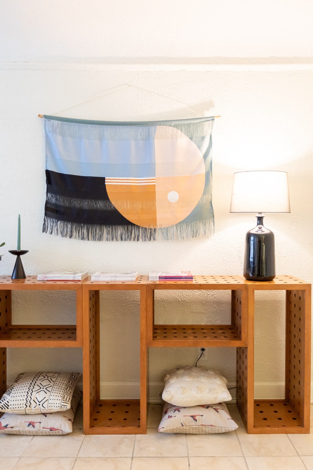 a room with a desk and a lamp and a tapestry on the wall