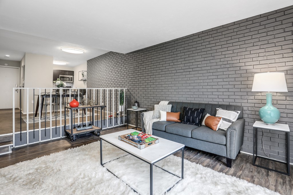 a living room with a couch and a table    and a brick wall