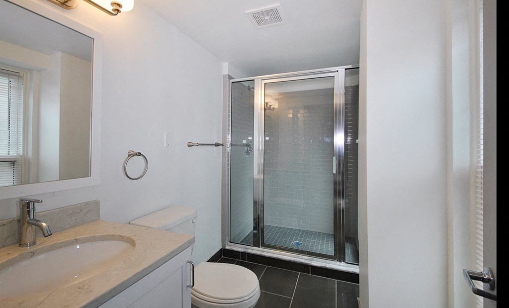 Updated modern bathroom with slate tile flooring and standing shower.