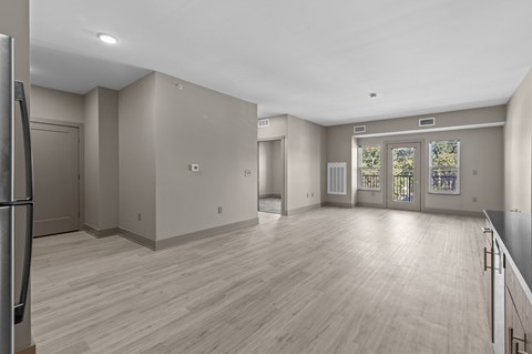 A spacious room with wooden flooring and a large window with a view of trees.