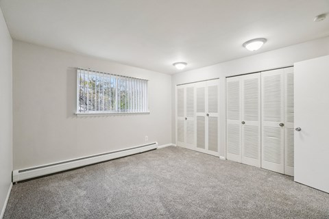 A room with white walls and a window with blinds.