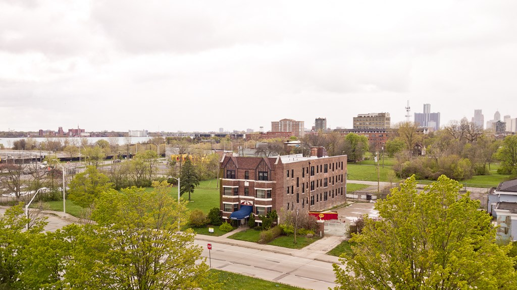 an aerial view of a brick building in a park with trees and a road in the foreground