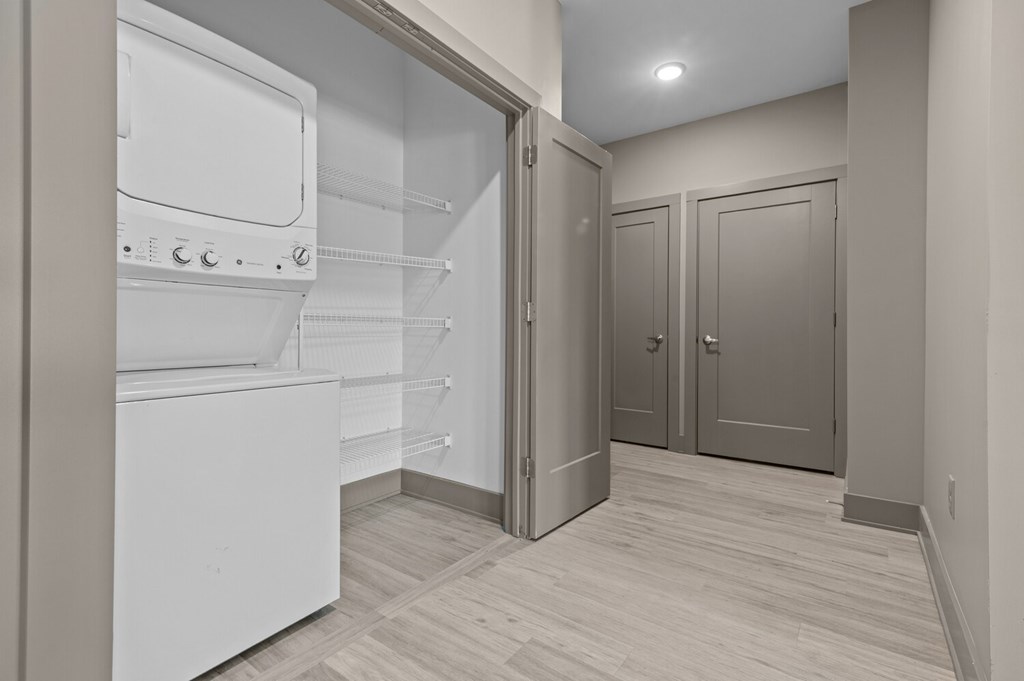 A kitchen with a white fridge and wooden floors.