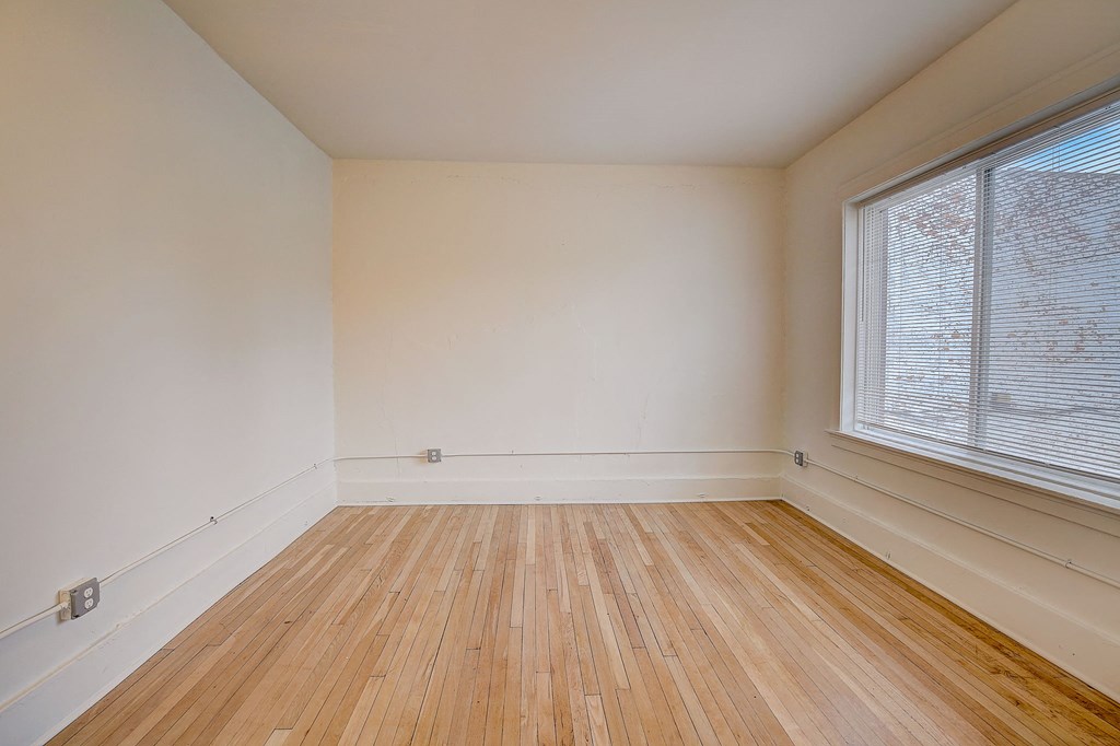 an empty room with wood floors and a large window