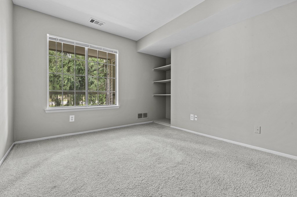 A room with a window and a carpeted floor.