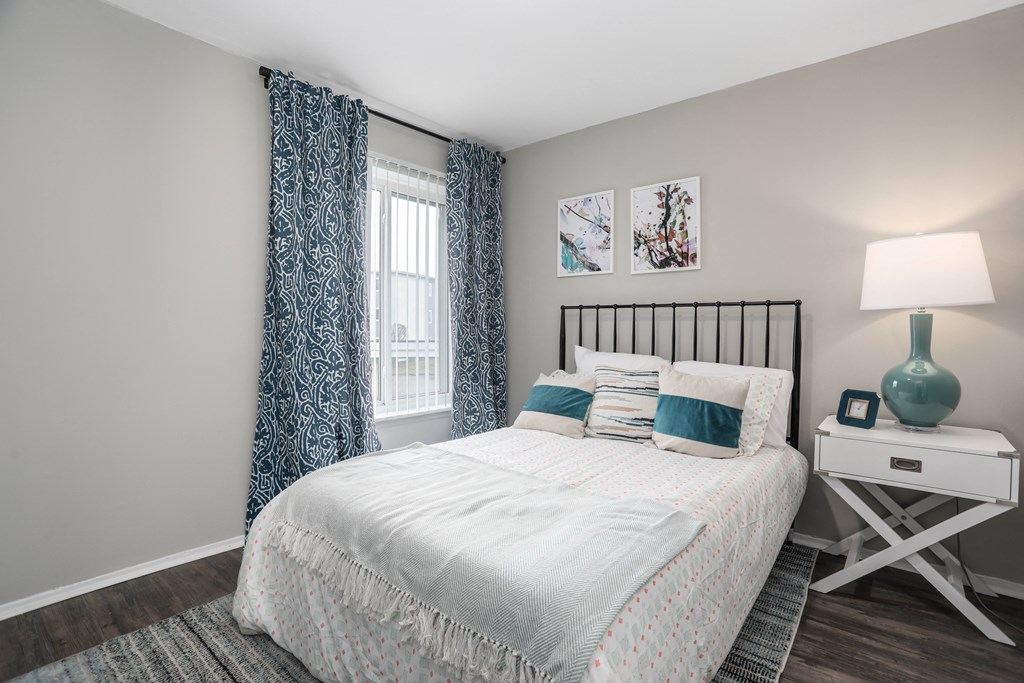 a bedroom with a bed and blue and white curtains and a window