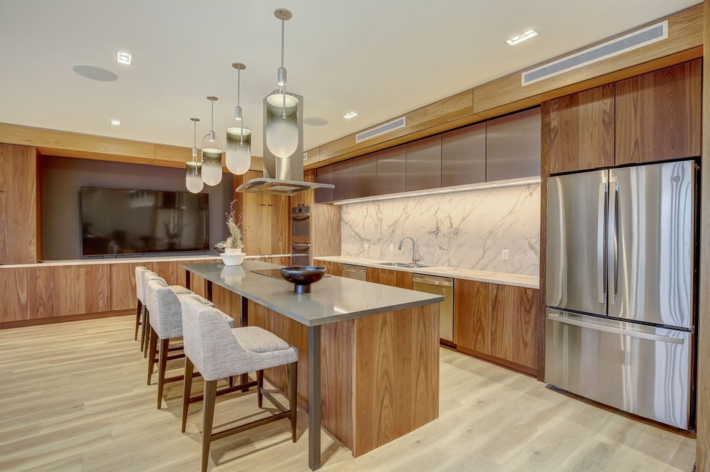 a kitchen with a large island and a stainless steel refrigerator